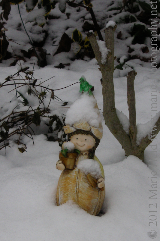 Snow-topped garden figurine.